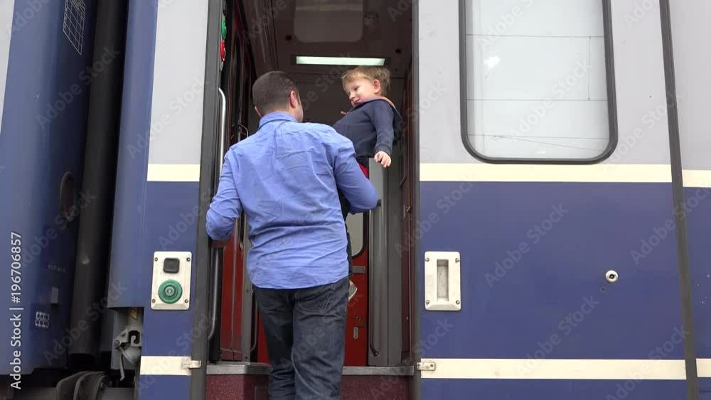 Father holding son going up in train boarding, family trip Father holding son going up in train boarding, family trip