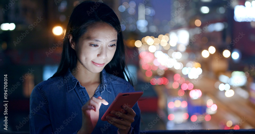 Woman use of smart phone over traffic background at night
