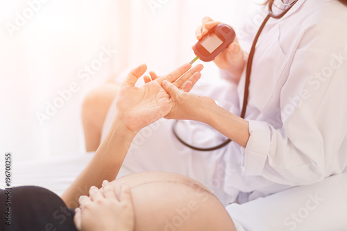 Female Obstetrician doctor  measuring blood sugar of the pregnant woman in the hospital. Gestational diabetes  mellitus concept.