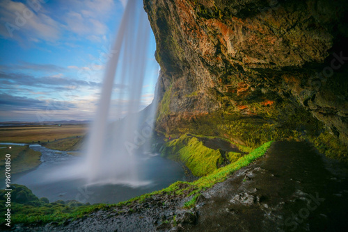 Big cave behind The Seljalandsfoss waterfall in Iceland with beautiful evening sky as background