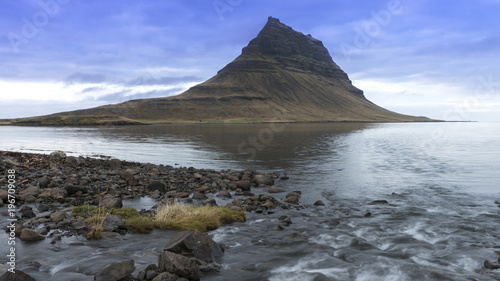 kirkjufell Mountain with a lake in foreground and blue cloudy sky