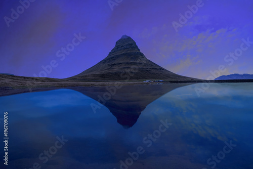 Kirjufell mountain with water reflection in the lake during purple sky of sunset