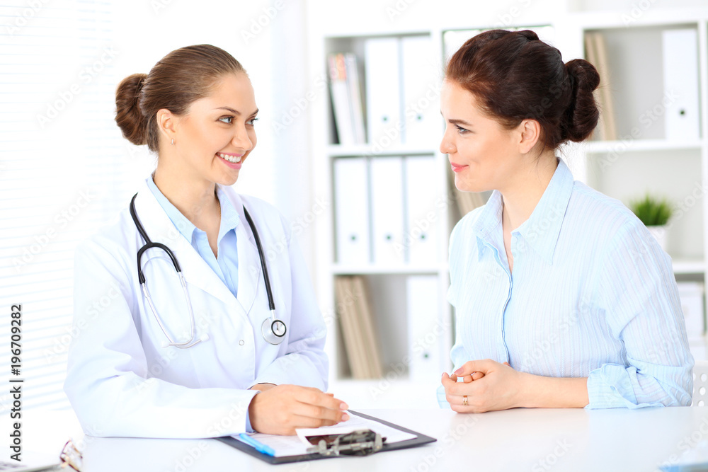 Friendly smiling doctor and patient sitting at the table Friendly smiling doctor and patient sitting at the table