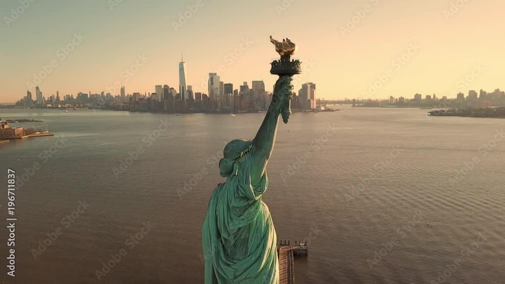 Statue of Liberty at beautiful sunset - aerial circling toward Manhattan skyline in New York City NYC in 4K and 1080 HD