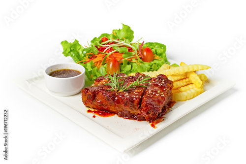 Roasted barbecue pork ribs served with french fries and salad on white background
