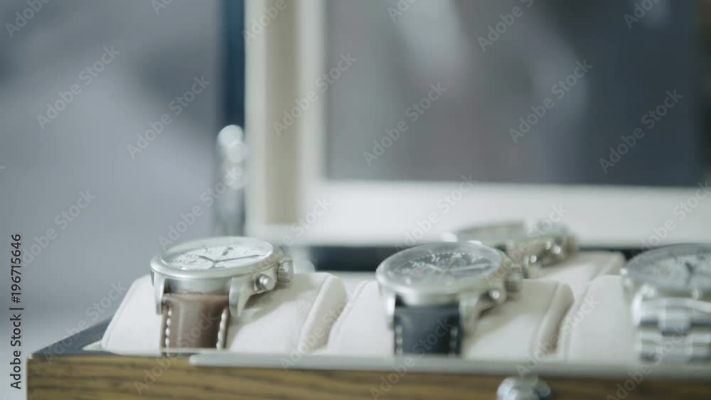 Box of watches with hand placing a watch and taking another Box of watches with hand placing a watch and taking another