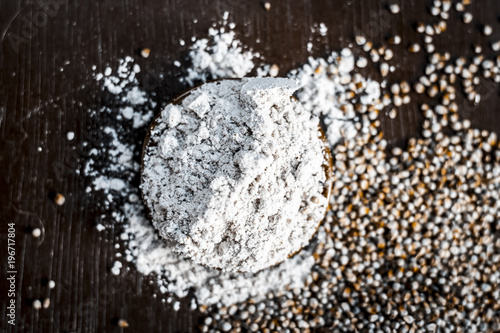 Close up of flour of pearl millet or bajra ka atta with raw pearl millet on a wooden surface in Dark Gothic colors. photo