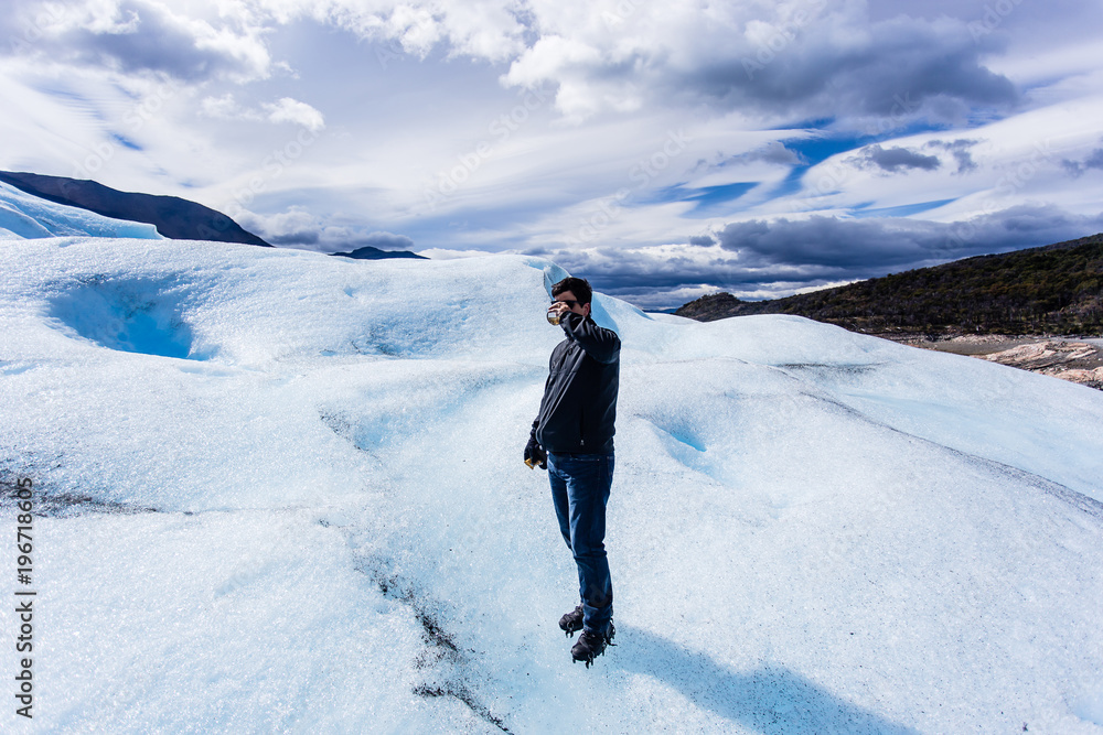 Man standing drinking whiskey on Glacier, black clothing, smilin