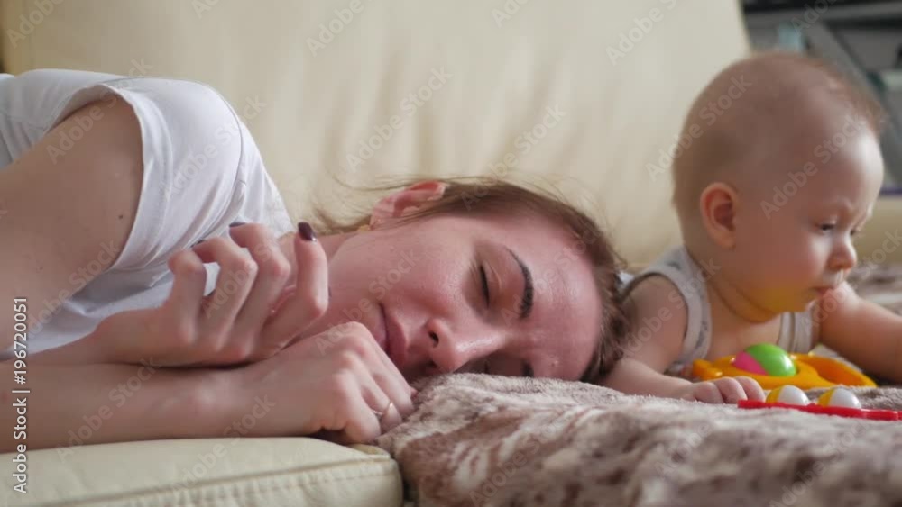 Tired young mother, fell asleep while her baby doesn't sleep Tired young mother, fell asleep while her baby doesn't sleep