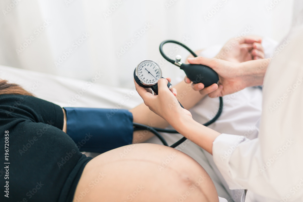 Fototapeta premium Female Obstetrician doctor measuring blood pressure of the pregnant woman in the hospital. Pregnancy-induced Hypertension concept.