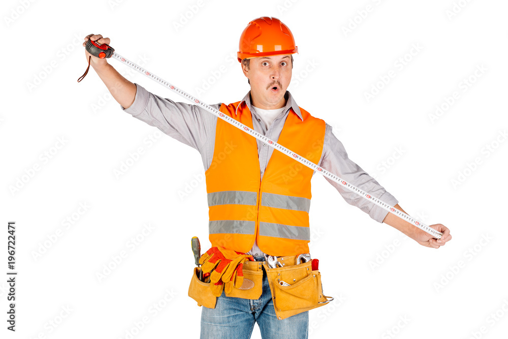 builder in a helmet holding tape-measure in his hands and looking at camera builder in a helmet holding tape-measure in his hands and looking at camera