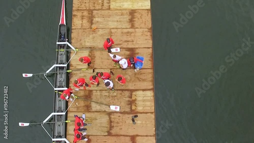 Rowing team unloading from boat onto dock, overhead aerial