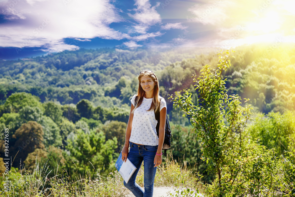 Happy young woman standing on top of mountain and enjoys view of mountains. (Travel, nature, adventure, victory concept)