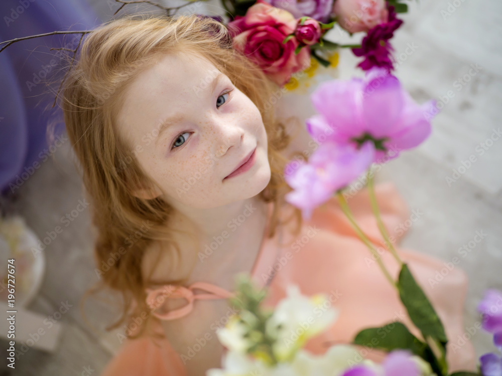 The beautiful face of a redheaded child is 9 years old in freckles in flowers. Spring