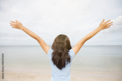 Asia girl with raised hands on the beach.
