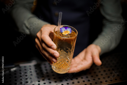 Bartender holding a sweet alcoholic cocktail decorated with a flower