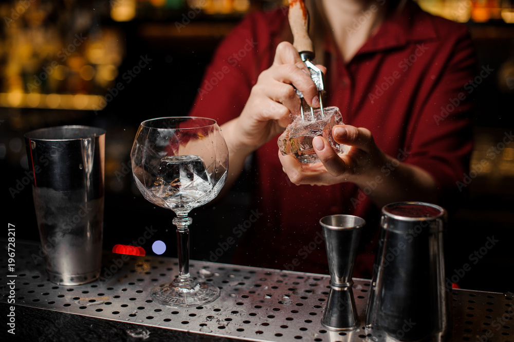 Female barman preparing ice cube for making cocktail