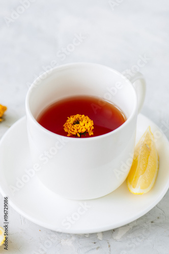 A cup of red herbal tea on a white stone backdrop. Close up.