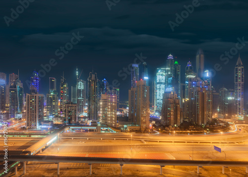Illuminated Dubai Marina skyline at cloudy night