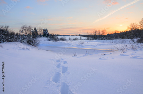 Frosty winter landscape with frozen river.Twilight.Cold morning.Snow covered trees.Sunrise.Footprints in drifts.River Torgosha in Moscow region,Russia. © valeriy boyarskiy