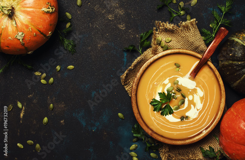 Cream pumpkin soup in a wooden bowl, rustic style, top view photo