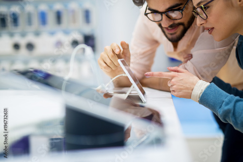Φωτογραφία Close up side view of curious charming happy young student love couple pointing to a new tablet in a tech store
