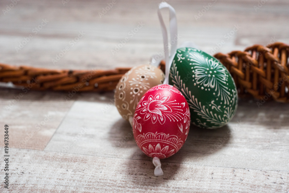 Obraz premium Homemade and handmade Easter eggs on birch branches on wooden tray, traditional czech, Easter egg hunt, whip with ribbons