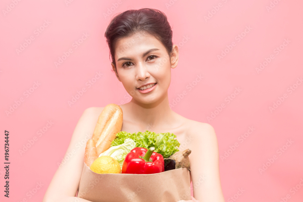 Woman holding shopping paper bag with fruit and vegetables diet healthy eating on pink background