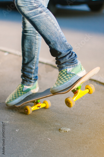 Skateboarder girl's legs in sneakers doing a trick on skateboard outdoors.