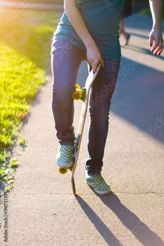 Skateboarder girl's legs in sneakers doing a trick on skateboard outdoors.
