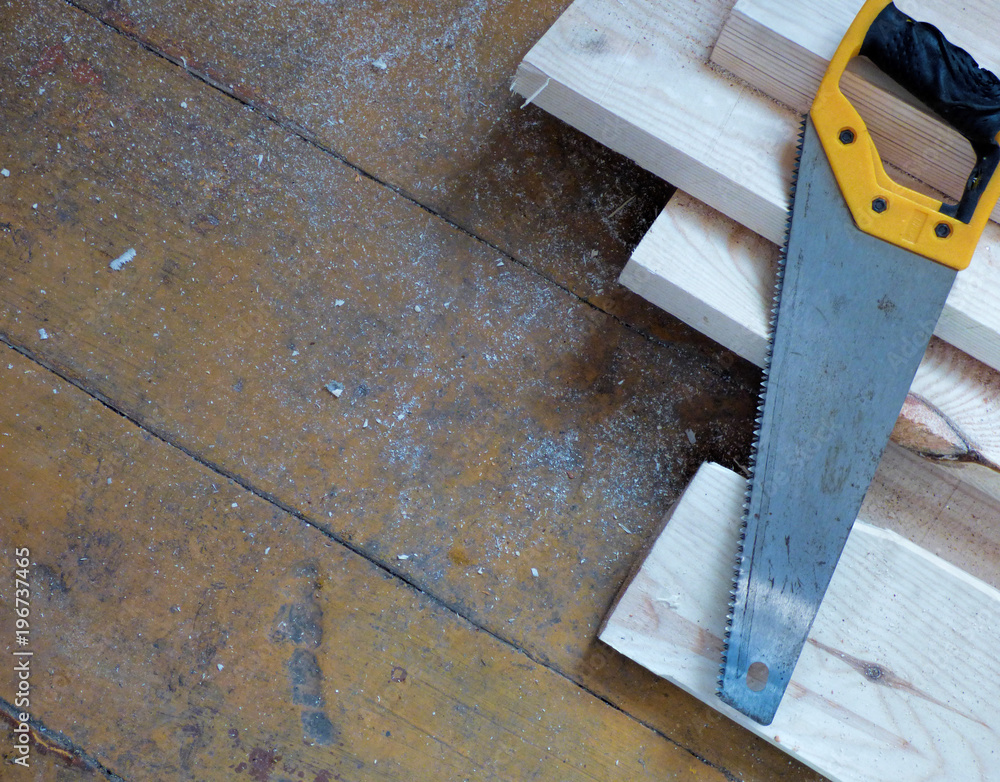 New fresh boards and saw on aged wooden surface (floor or table). Abstract background. Natural materials - two kinds of wood. New fresh boards and saw on aged wooden surface (floor or table). Abstract background. Natural materials - two kinds of wood.