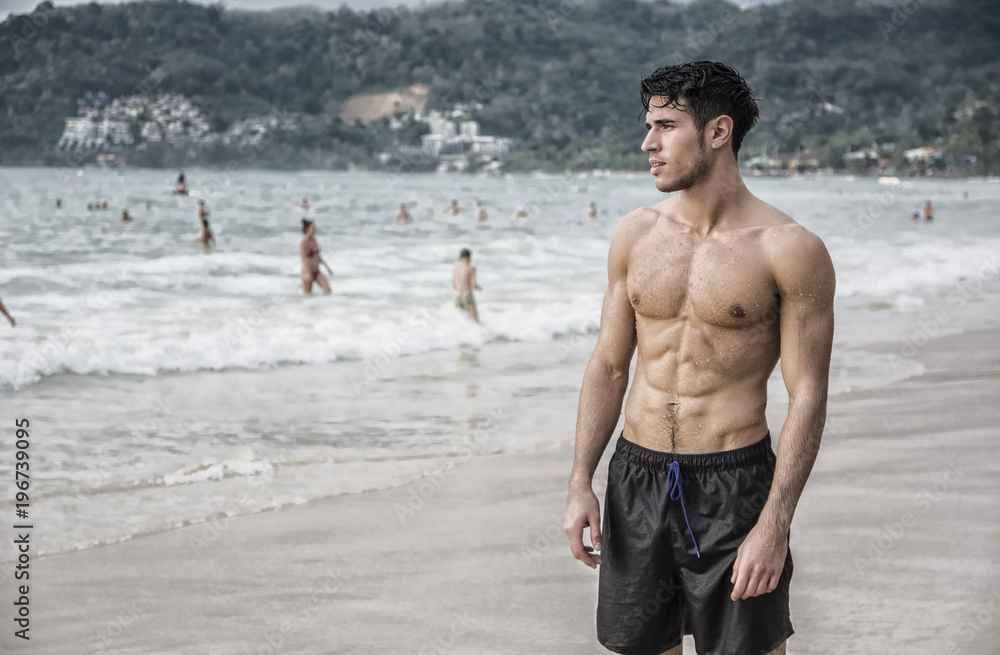 Half body back shot of a handsome young man standing on a beach in