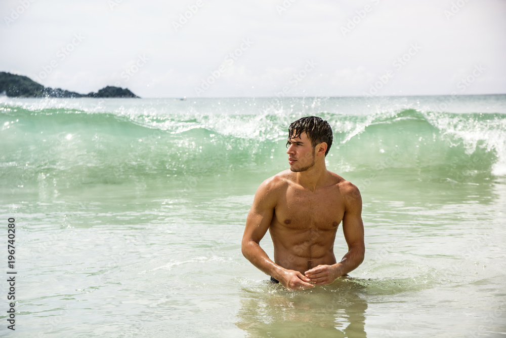Handsome young man standing on a beach in Phuket Island, Thailand, shirtless wearing boxer shorts, showing muscular fit body Handsome young man standing on a beach in Phuket Island, Thailand, shirtless wearing boxer shorts, showing muscular fit body