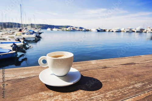 Coffee cup on a wood table over blue sky and sea background. Summer holiday concept