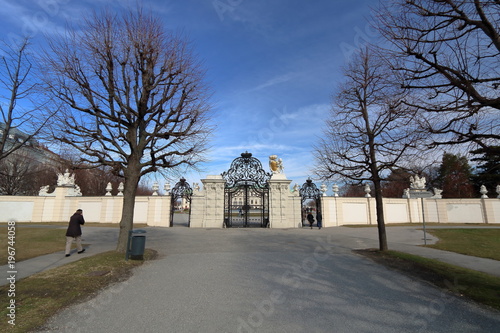 Jesienny widok głównej bramy wjazdowej do pałacu Belvedere w Wiedniu, Austria, jesienne bezlistne dzrewa, jeden turysta, piękne niebieskie niebo