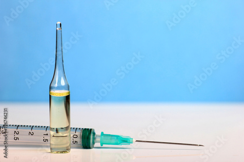 Set Ampule medical glass on white table with blue background. Syringe, needle.