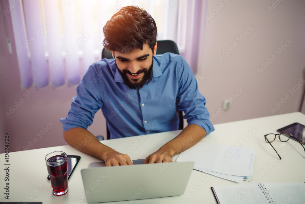 Confident young businessman working on a laptop in the office. Confident young businessman working on a laptop in the office.