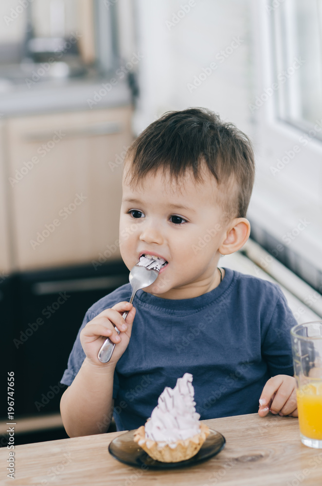 the child in the kitchen eating a cake with cream is very appetizing, spoon the child in the kitchen eating a cake with cream is very appetizing, spoon