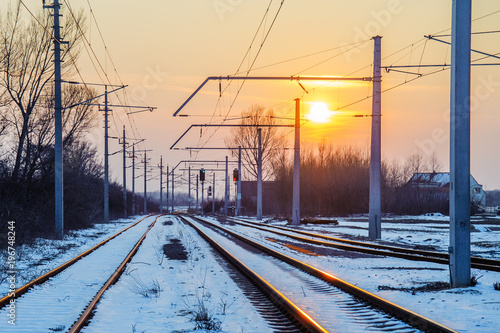 Schienen einer Bahnlinie im Schnee bei untergehender Sonne