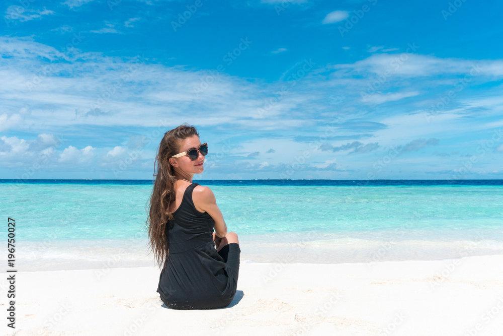 Woman sitting on beach with transparent water of ocean in Maldives Woman sitting on beach with transparent water of ocean in Maldives
