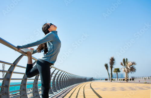 Fototapeta Naklejka Na Ścianę i Meble -  Girl warming up for a workout by the seaside