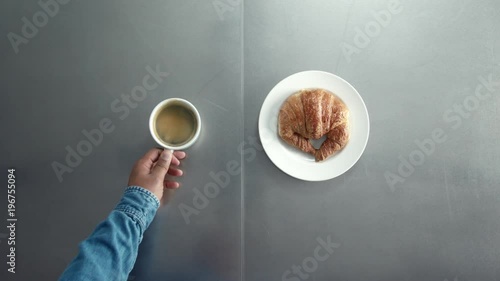 breakfast with coffe and croisant top view how man's hand put on table dish with croissant and cup of coffe