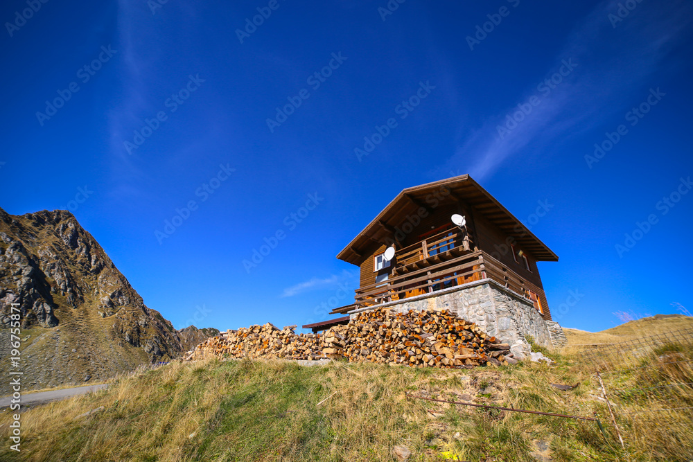 Autumn landscape with wood pile in front of cabin and Fagaras mountains in the background at the Balea Lake, in Sibiu county, Romania