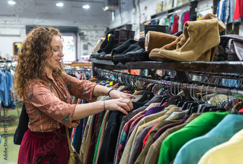 Woman browsing through vintage clothing in a Thrift Store.