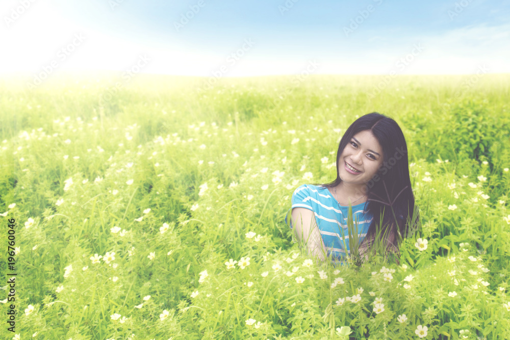 Fototapeta premium Beautiful woman sitting on the blossom meadow