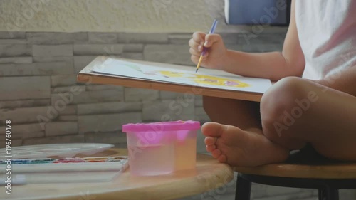 Child girl drawing by watercolor at home in slow motion. photo