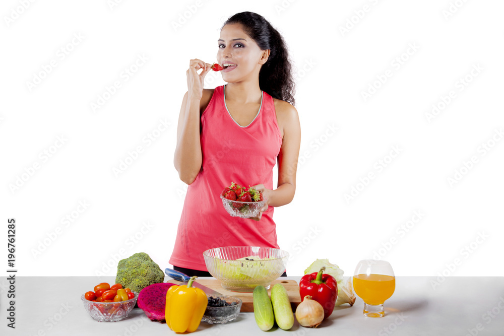 African woman eating fresh strawberry on studio African woman eating fresh strawberry on studio