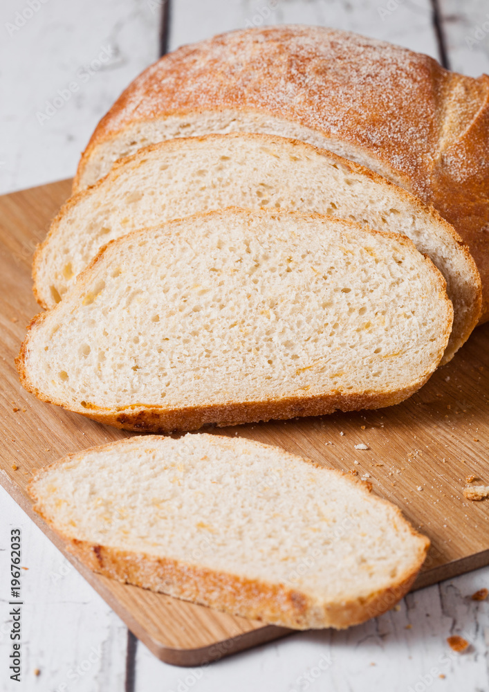 Freshly baked bread loaf with pieces on wood board