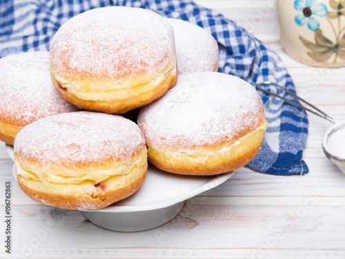Traditional Polish donuts with powdered sugar on wooden background. Tasty doughnuts with jam.