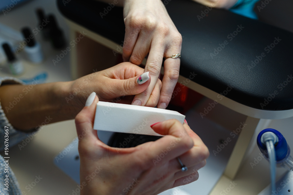 Close-up professional manicure pedicure polishing nail file client.